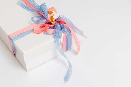 Gift box tied with blue and pink ribbons on white backgroundの写真素材