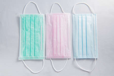 Pink, green and blue medical face mask and coronavirus protection isolated on a white background,...