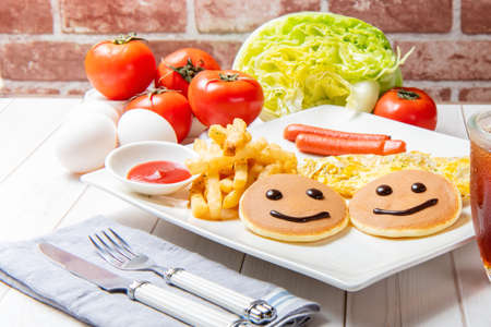 Breakfast with pancakes, french fries, German sausages, eggs, vegetables and drinks is on the table
の写真素材