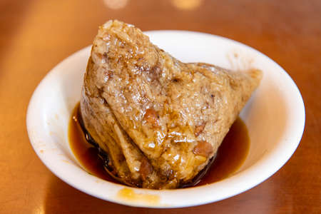 rice dumpling is a traditional Chinese rice dish made of glutinous rice and wrapped in bamboo leaves, Dragon Boat Festival is making and eating zongzi with familyの写真素材