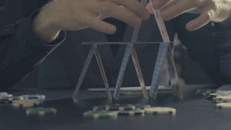 Man's hands building a house of a playing cards. Close up