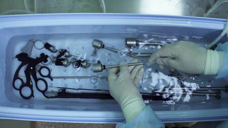 Close up of nurse's hands washing medical instrument after operationの写真素材
