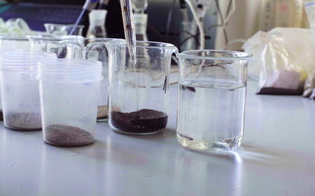 Water pouring in chemical beakers with the soil
