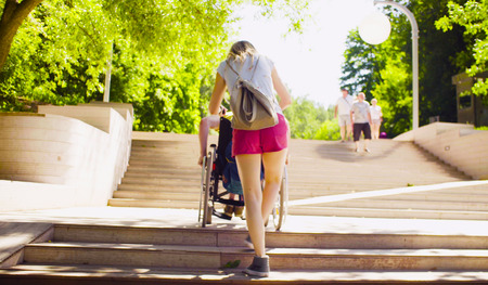 Disable man in a wheelchair is moving down the stepsの写真素材