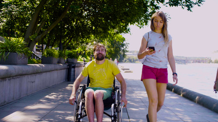 Young disable man on a walk near the river with his wife