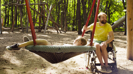 Woman is lying on a swing and a man is pushing a swingの写真素材