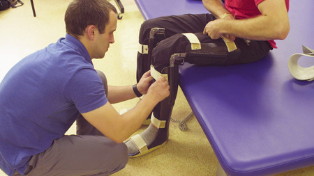Doctor physiotherapist putting the orthosis for disabled man
