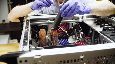 Male hands cleaning computer system from dust