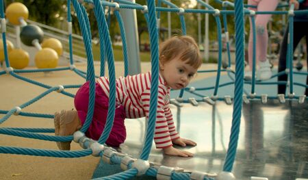 Baby girl sitting on all fours on the children's trampolineの写真素材