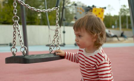 Baby girl near the swing on the playground