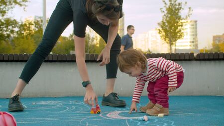 Young woman playing with the small girl on the playgroundの写真素材