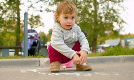 Small cute girl drawing on asphalt in the parkの写真素材