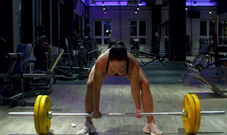 Woman bodybuilder lifting barbell. Athlete in the gym. Fitness, sport, and training conceptの写真素材