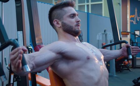 Strong bodybuilder doing hand exercises in the gym