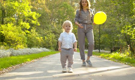Young attractive mother and funny baby in the park. Mom holding a balloon. Family, Mother's Day