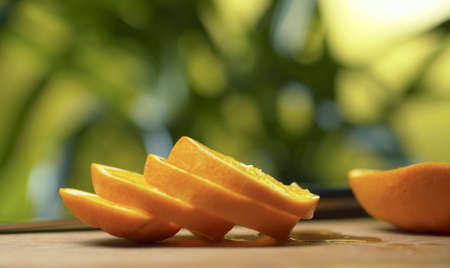 Close up sliced orange on the table over blurred natural background. Drops of juice on a table....