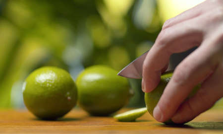 Close up male hand cutting a lime on green natural background. Making drinks. Healthy lifestyle and eating concept.の写真素材
