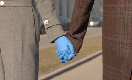 Close up hands of couple in blue latex gloves walking during coronavirus epidemicの写真素材