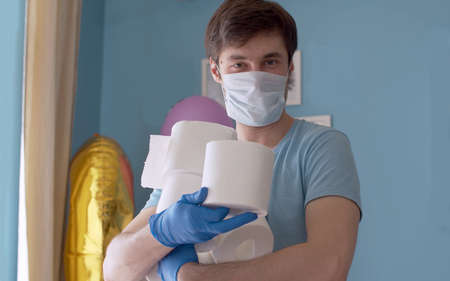 Coronavirus panic buying humor. Funny man holding many rolls of toilet paper, he bought in...