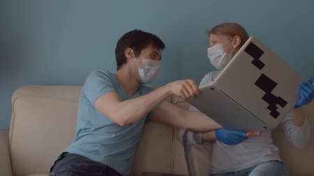 Home office. Family on remote job. A woman takes a computer from her husband, he does not agree....