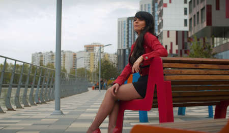 Portrait of beautiful brunette woman with long hair sitting on the bench in the city near the river. Real people.の写真素材