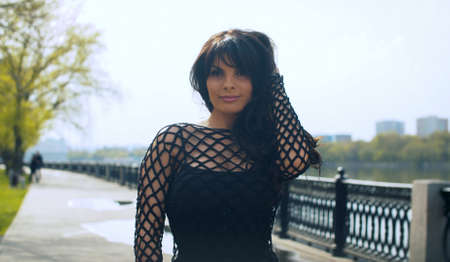 Beautiful smiling woman in black clothes on the embankment in the city park. Nice early spring day....