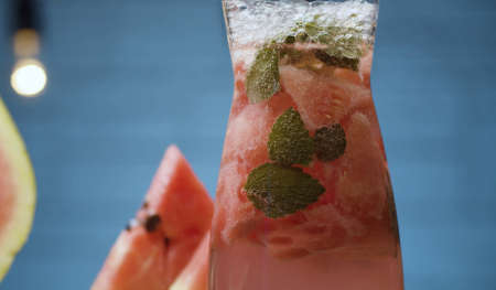 Close up watermelon lemonade in a glass jug. Soda water, pieces of watermelon, mint leaves and ice...
