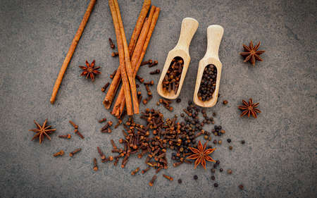 Various of spices and herbs in wooden spoons. Flat lay spices ingredients clove ,peppercorn, cinnamon and star anise on dark stone background.の写真素材