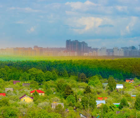 The Stand near Moscow: Countryside, forest line, wall of rain and rainbow VS frontal attacking city. Village in focus, City - under rain counter-attackの写真素材