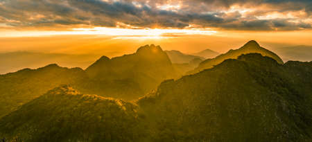beautiful mountain peaks topped with sky, cloud and sun flaresの写真素材
