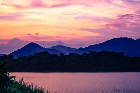 silhouette mountain with attractive background, sunset with vivid purple sky and lakeの写真素材