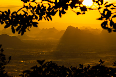 A beuatiful view of mountain ridges with the blurred leafs frame and morning sky background at Phu Kra Dung National park of Thailandの写真素材