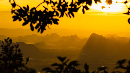 A beuatiful view of mountain ridges with the blurred leafs frame and morning sky background at Phu Kra Dung National park of Thailand, in panoramic style.の写真素材