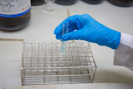 chemist shaking the blue clear reagent into test tube for reaction testing in chemical laboratory,...