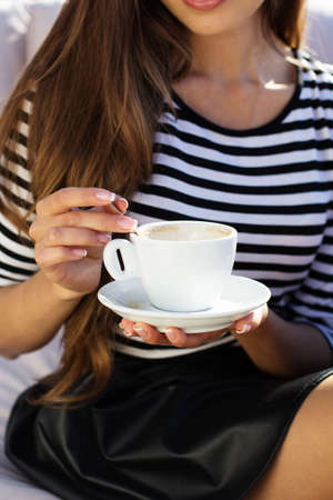 Young woman drinking coffee  in a cafe outdoors. Summer timeの写真素材