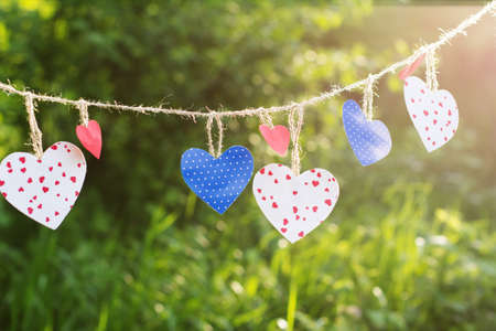 Colorful textured hearts hanging on green grass backgroundの写真素材