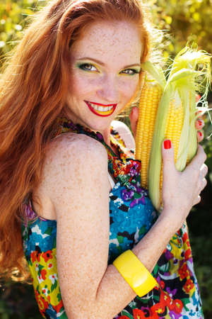 Smiling girl with freckles holding corn cobの写真素材