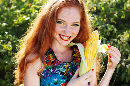 Smiling girl with freckles holding corn cobの写真素材