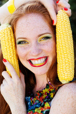 Smiling girl with freckles holding corn cob