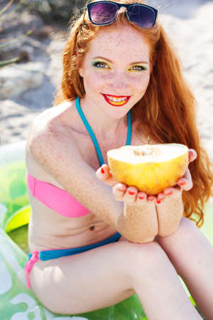 Smiling girl with freckles holding melonの写真素材