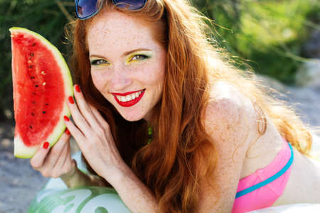 Smiling girl with freckles holding watermelonの写真素材