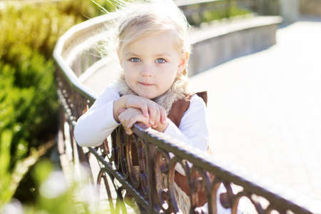 Little girl is sitting on the bench, autumn time