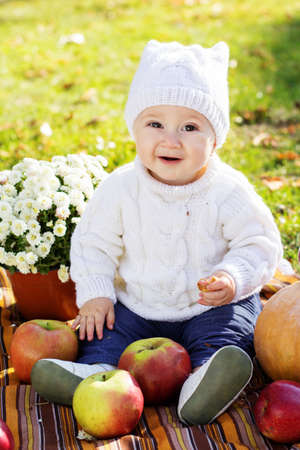 Baby boy with pumpkins in autumn park