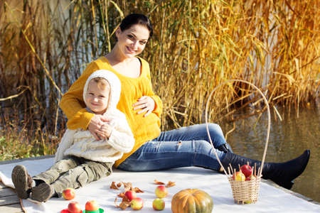 Little boy with her mother on the autumn lake