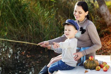 Little boy with her mother on the autumn lakeの写真素材