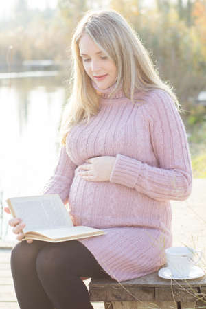Pregnant woman on the autumn lakeの写真素材