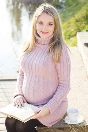 Pregnant woman on the autumn lakeの写真素材