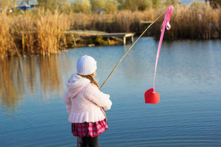 Little girl fishing from dock on lake.の写真素材