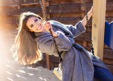 Young fashion girl having fun on swingの写真素材