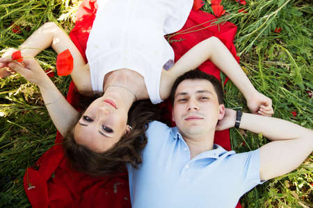 Young happy couple on a meadow full of poppiesの写真素材